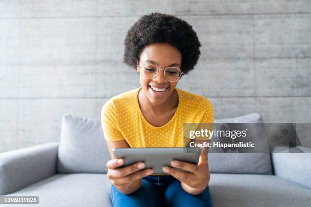 happy woman at home watching videos online on a tablet - using digital tablet 個照片及圖片檔