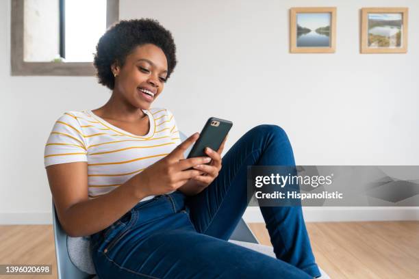 happy woman at home texting on her cell phone and smiling - search new home stock pictures, royalty-free photos & images