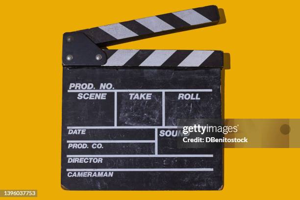 old wooden movie clapperboard with hard shadow on yellow background. concept of film industry, cinema, entertainment, and hollywood. - câmara de filmar imagens e fotografias de stock