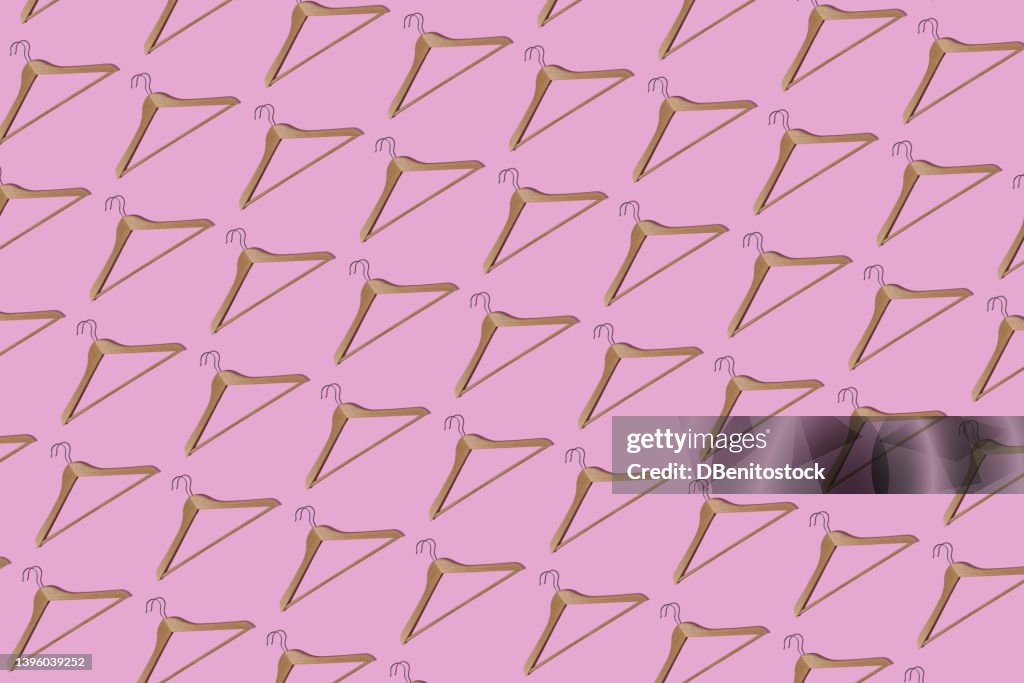 Pattern of wooden hangers with hard shadow on pink background. Clothes, store, closet, organization, wardrobe, business, textile and clothes sale concept.