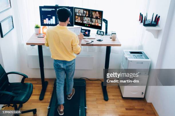 mann im home office am stehpult, der über einen geschäftlichen videoanruf spricht - ergonomie stock-fotos und bilder