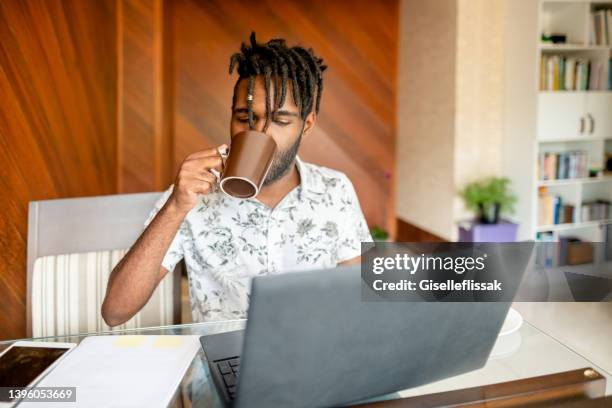 african man drinking coffee while working at home office - resourceful bildbanksfoton och bilder