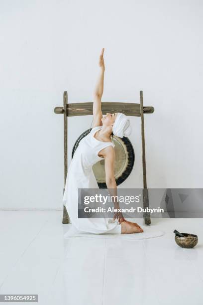 beautiful young woman practices yoga doing beautiful exercise - gong fotografías e imágenes de stock