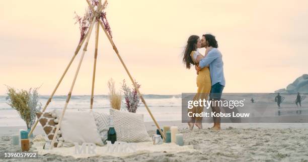 a happy young couple hugging and embracing on the beach after their proposal. a man and woman in love, kissing and celebrating their engagement - romantic picnic stockfoto's en -beelden