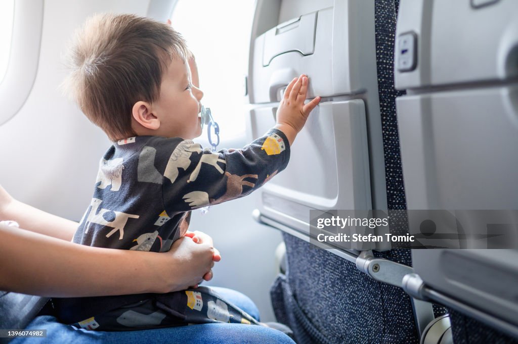 Baby traveling in airplane flying sitting on his mother lap in the aircraft