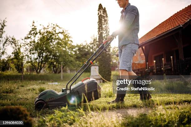 man mowing grass near his house - lawn mower stock pictures, royalty-free photos & images