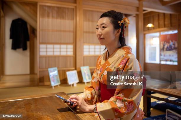 japanese woman in kimono sitting on heels and reading message on smartphone - washitsu stock pictures, royalty-free photos & images