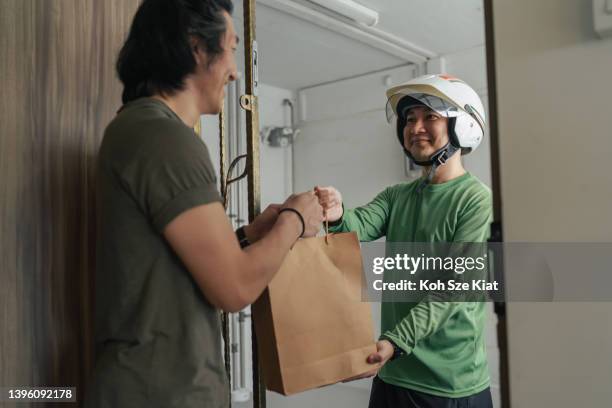 customer satisfaction - delivery rider successfully delivers food to customer at the doorstep - gig economy stock pictures, royalty-free photos & images