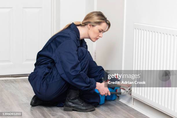 female plumber fixing a radiator - blue jumpsuit stock pictures, royalty-free photos & images