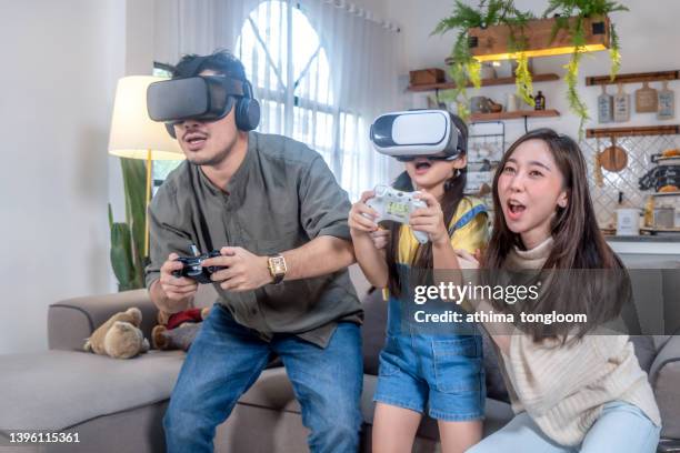 cheerful family having fun with new trends in technology playing virtual reality headset. - fashionable dad stock pictures, royalty-free photos & images