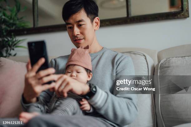 father working at home while taking care of his baby - two people video conferencing stock pictures, royalty-free photos & images