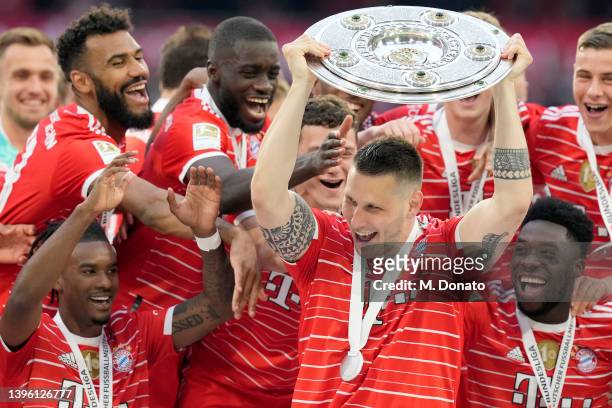 Niklas Süle of Bayern Muenchen lifts the championship trophy and celebrates winning the championship with his team after the Bundesliga match between...