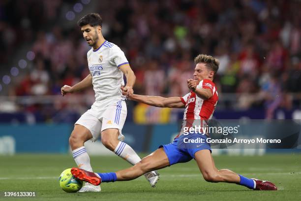 Marco Asensio of Real Madrid CF competes for the ball with Marcos Llorente of Atletico de Madrid during the La Liga Santander match between Club...