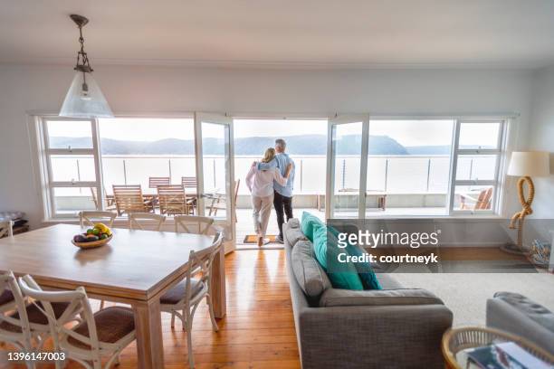 mature couple looking at the view in their waterfront home. - holiday villa bildbanksfoton och bilder