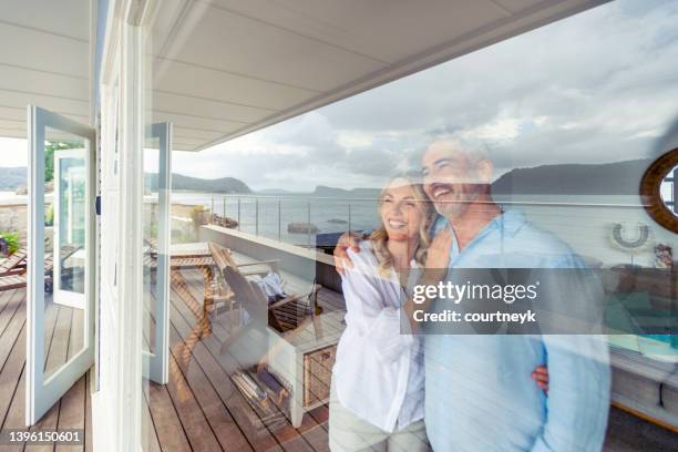mature couple looking at the view in their waterfront home. - secluded couple stockfoto's en -beelden