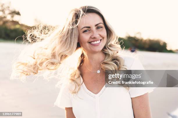 smiling woman at beach with blonde hair - model hair natural stock pictures, royalty-free photos & images