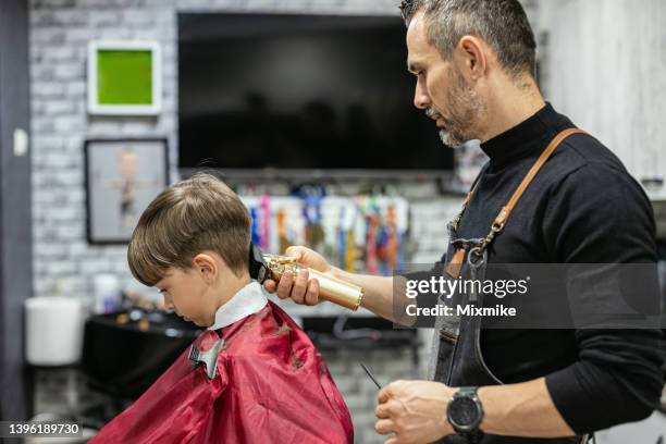 cute boy getting haircut at hair salon - hair salon imagens e fotografias de stock