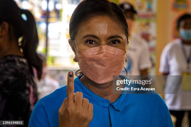 Vice President Leni Robredo shows her finger with indelible ink after casting her vote at a school converted into a polling precinct on May 9, 2022...