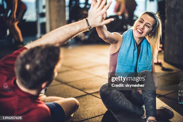 happy athletic woman giving high-five to her friend on a break in a gym. - working out stock pictures, royalty-free photos & images