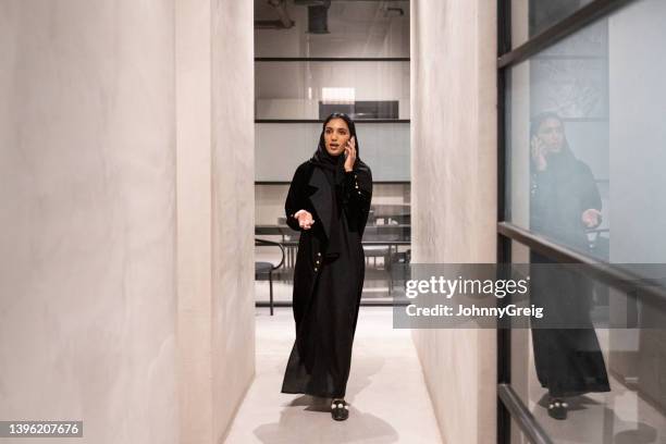 young middle eastern businesswoman talking on smart phone - arab woman walking stockfoto's en -beelden