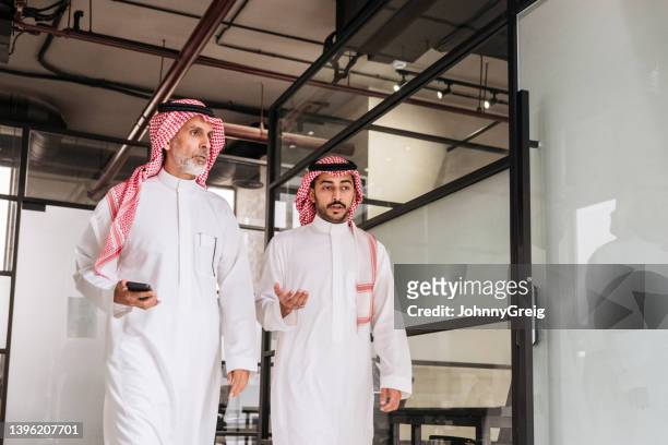 bearded executives walking through modern riyadh office - arab man walking stock pictures, royalty-free photos & images