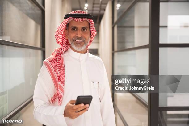 fröhlicher geschäftsmann aus dem nahen osten mit smartphone - saudi arabia business stock-fotos und bilder