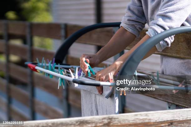 unrecognizable woman hanging clothes in pajamas on clothesline outdoors in sunny weather - clothes peg stock pictures, royalty-free photos & images