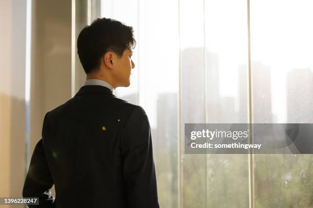 young asian businessmen look at the city skyline through their office windows - corporate skyline stock pictures, royalty-free photos & images