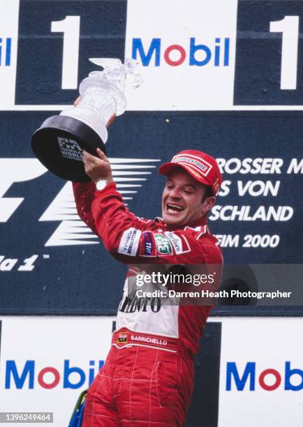 Rubens Barrichello of Brazil, driver of the Scuderia Ferrari Marlboro Ferrari F1-F2000 Ferrari V10 holds the trophy aloft and celebrates his first...