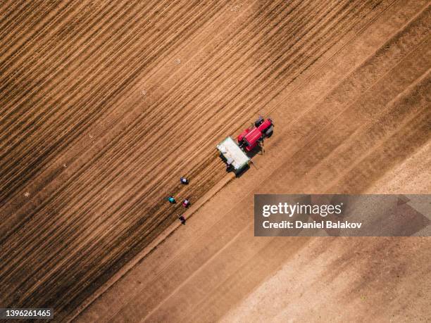 vista aérea de tractores arando y agricultores sembrando un campo agrícola. - campo arado fotografías e imágenes de stock