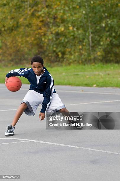 africanamerican 13 year old teen playing basketball by himself on an outside court at a park - african american teen stockfoto's en -beelden