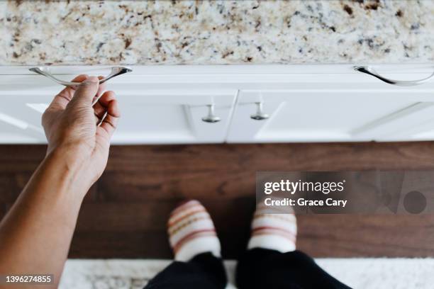 woman opens kitchen drawer - kitchen bench from above stock-fotos und bilder