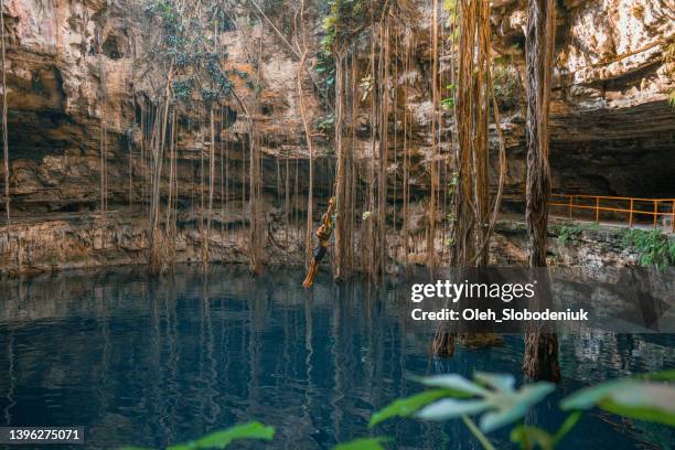 man on rope swing in cenote - rope swing stock pictures, royalty-free photos & images