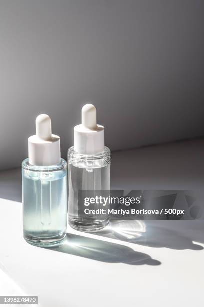 two laconic bottles of cosmetic liquid in the rays of the harsh sun - solid perfume stock pictures, royalty-free photos & images