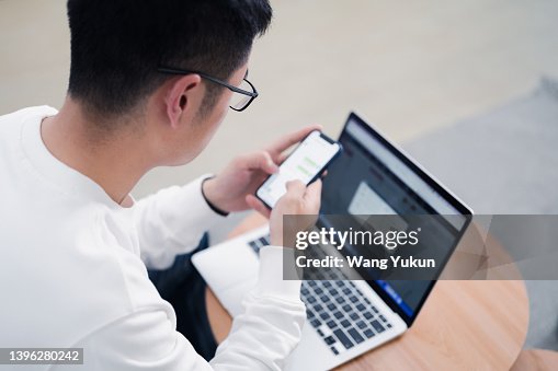 Back View Of Young Man Working At Home Using Computer And Smartphone ...