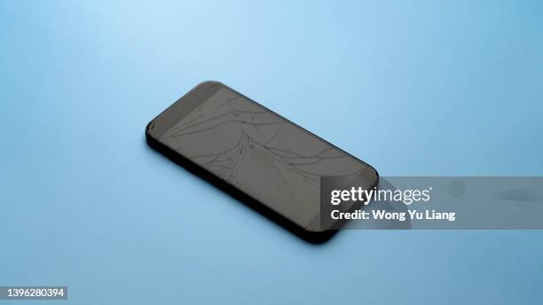 broken phone on the blue table background - repairing iphone stock pictures, royalty-free photos & images