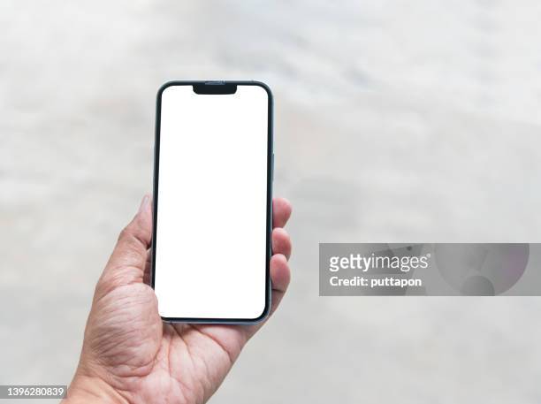 close up of man hand holding smartphone on white background, cropped hand using smartphone on the background of polished cement - stock photo - smartphone mockup stock-fotos und bilder