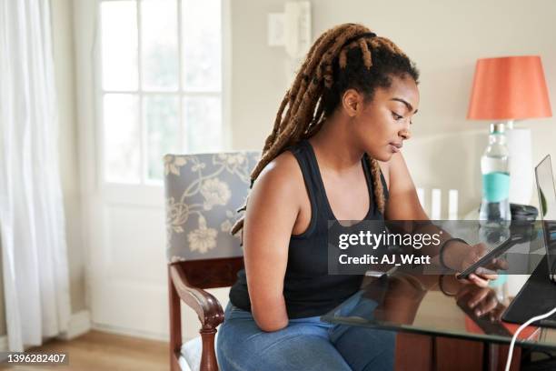 beautiful african woman using mobile phone sitting at home - amputee home stock pictures, royalty-free photos & images