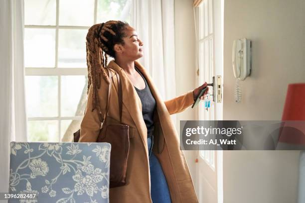 african woman leaves house carrying purse - black purse stockfoto's en -beelden