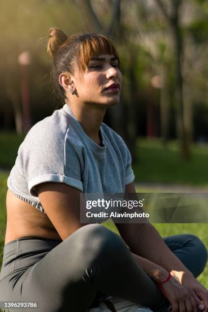 portrait of a relaxed transgender transsexual woman sitting in an archway enjoying the sun. concept of relaxation and freedom. - transgender athlete stock pictures, royalty-free photos & images
