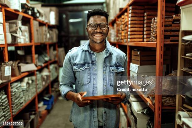 young handsome man posing near shelf in distribution warehouse - retail manager stock pictures, royalty-free photos & images