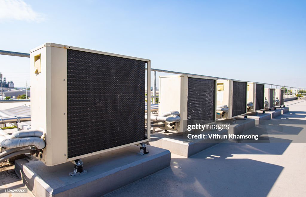 Air compressor machine part of air conditioner system on roof deck with sky background at factory.