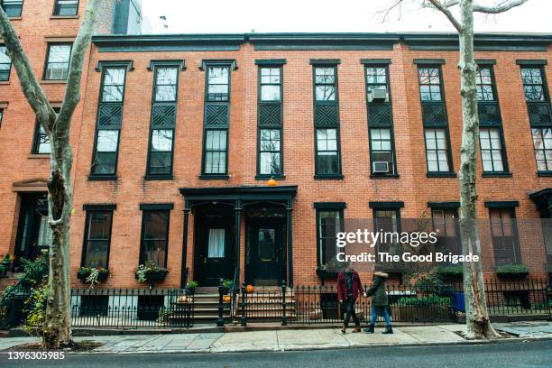 wide shot of couple walking in front of residential building - brooklyn brownstone bildbanksfoton och bilder