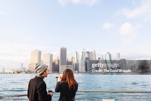 rear view of young couple looking at manhattan skyline from brooklyn - age of extinction new york premiere stockfoto's en -beelden