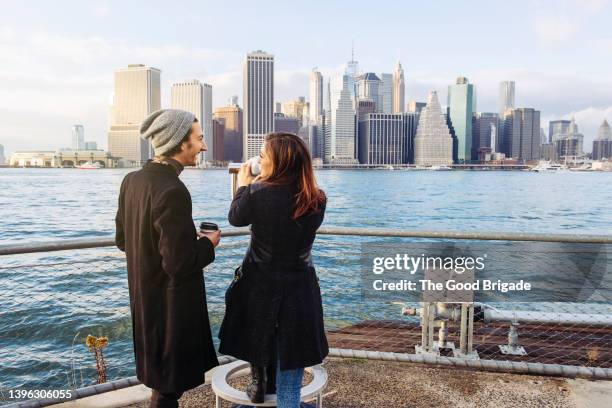 rear view of young couple looking at manhattan skyline from brooklyn - north america skyline stock pictures, royalty-free photos & images