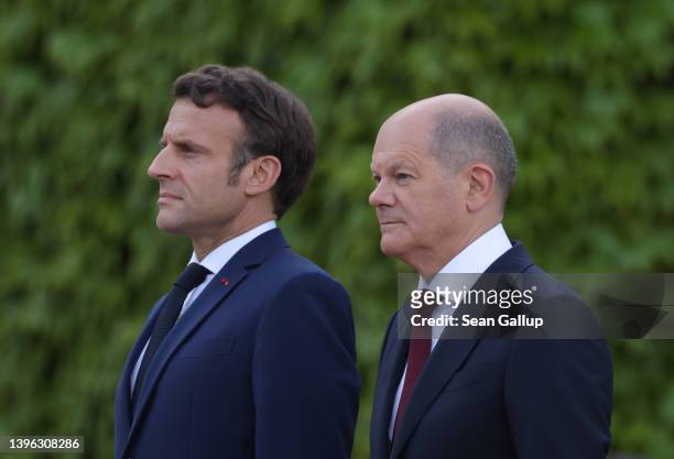 German Chancellor Olaf Scholz and French President Emmanuel Macron listen to their nations' national anthems upon Macron's arrival for talks at the...