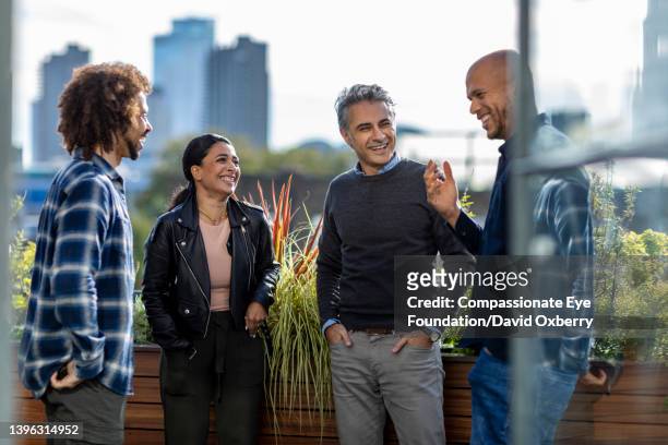 coworkers talking  on sunny urban rooftop - coworkers outside stock pictures, royalty-free photos & images