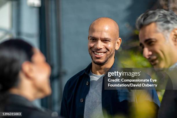 coworkers talking  on sunny urban rooftop - 3 men standing outdoors stock pictures, royalty-free photos & images