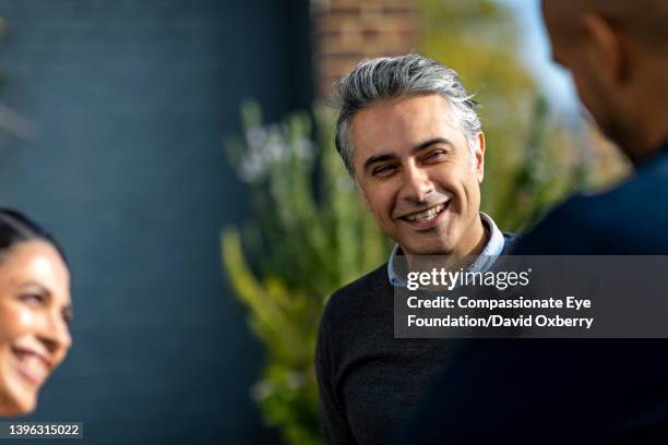 coworkers talking  on sunny urban rooftop - casual professional man stockfoto's en -beelden