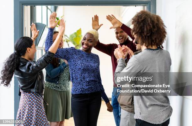 business people high fiving in office - high five stock pictures, royalty-free photos & images